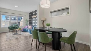 Una sala de estar moderna con comedor, un ventanal grande y un muro decorativo.
