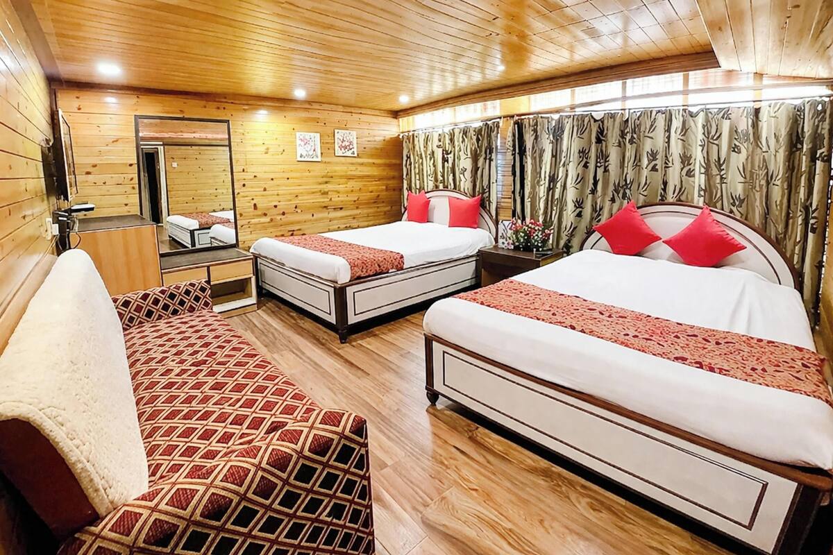 Une chambre de style cabane avec des murs en bois, deux lits avec des oreillers rouges, un canapé et un miroir.
