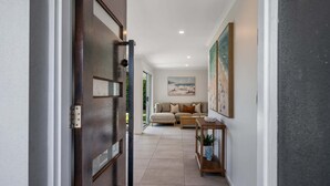 A hallway with a dark door, a beige sofa, a small table, and a painting on the wall. - Mooloolaba Canal Retreat with Pool, Sleeps 12 (Mooloolaba)