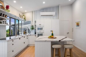 Een moderne keuken met witte kastjes, een marmeren eiland en een ingebouwde airconditioning.