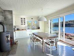 Une cuisine moderne avec des meubles blancs, une grande table en bois et une vue sur un lac.