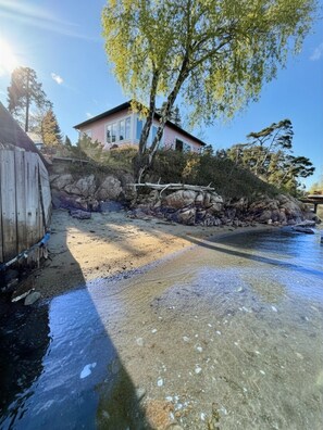 Ein Küsteneigentum mit freiem Blick auf das Meer, einem Holzzaun und einem Haus mit rosafarbenem Mauerwerk.