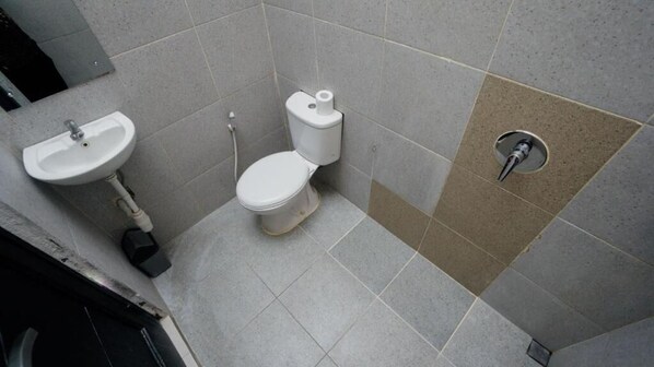 A bathroom with a sink, toilet, and a shower drain. - Escotel Tempekan Canggu (Tibubeneng)