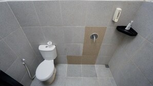 A bathroom with a toilet, a shower, and a soap dispenser. - Escotel Tempekan Canggu (Tibubeneng)