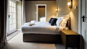 Un dormitorio con una cama grande, una mesita de noche, una lámpara de pared y una puerta con vistas.