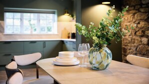 Una mesa de comedor con platos, vasos y un florero con plantas.