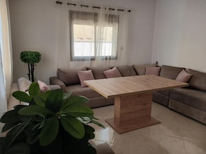 Una sala de estar con una mesa de centro de madera, un sofá y una planta en maceta.