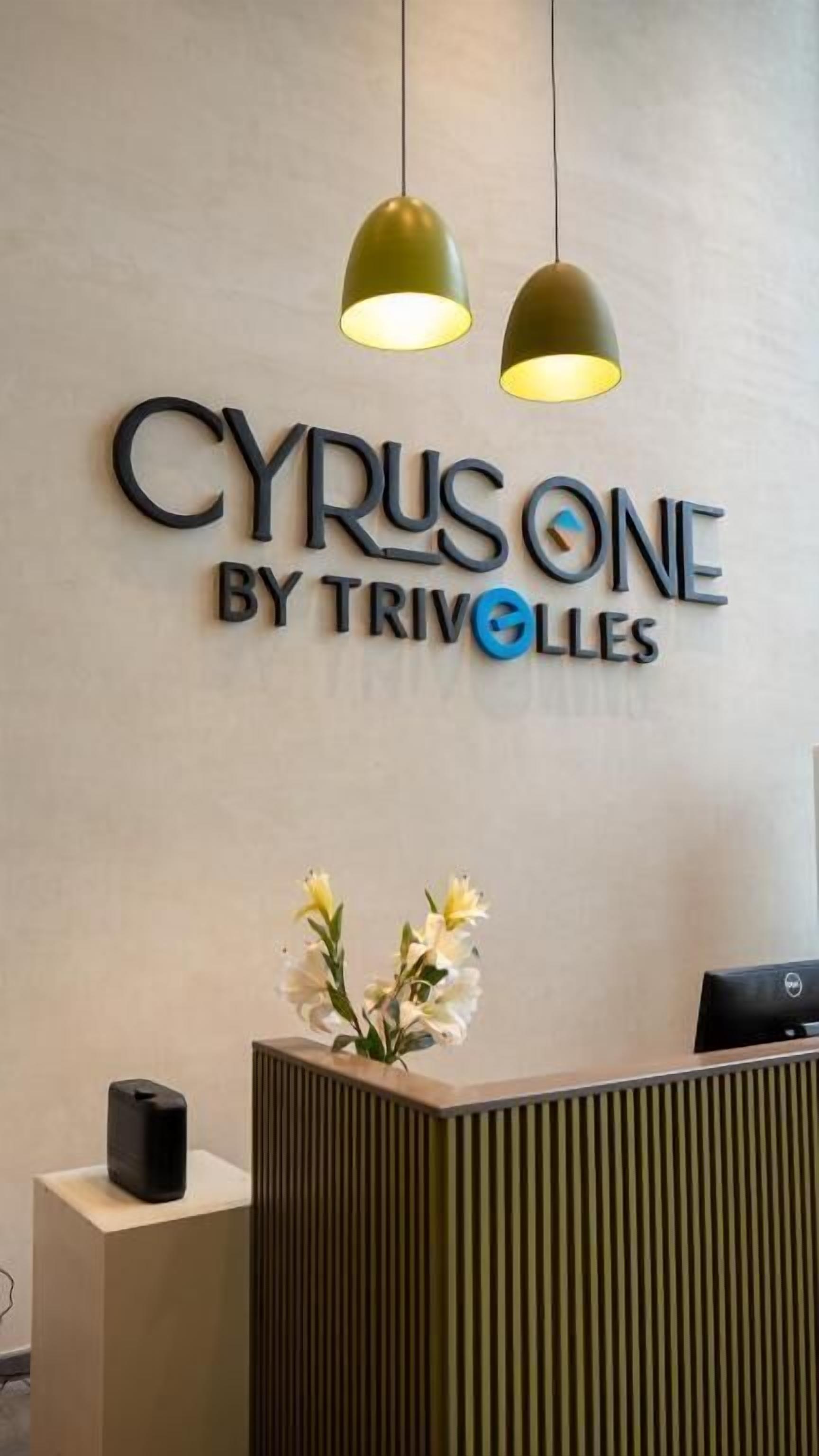 A reception desk with a sign reading 'CYRUSONE BY TRIVOLLES' and two pendant lights above it.