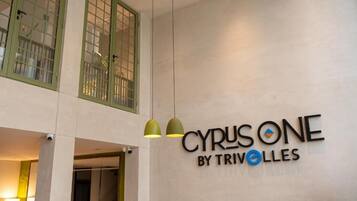 A hotel sign with the name 'CYRUSONE BY TRIVOLLES' and a modern interior with pendant lighting.