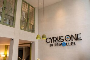 A hotel sign with the name 'CYRUSONE BY TRIVOLLES' and a modern interior with pendant lighting.