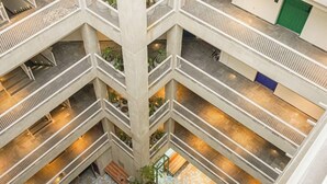 En fleretages atrium med et stort, åbent rum i midten, flere etager og forskellige siddeområder.