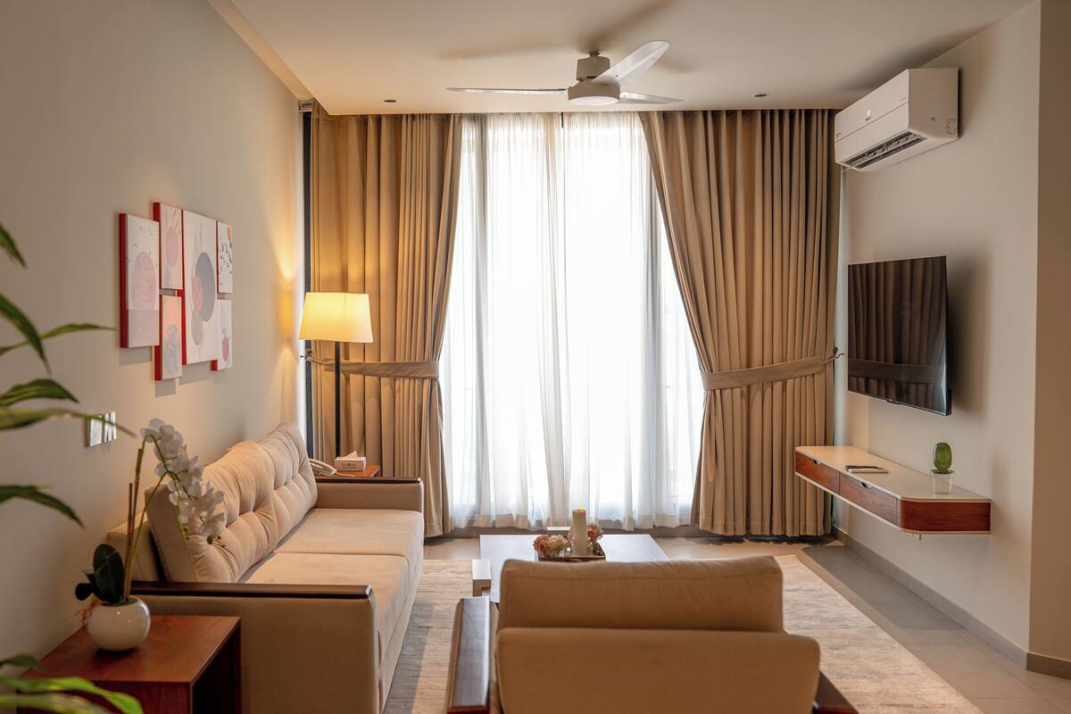 A hotel room with a sofa, a coffee table, a TV, and a ceiling fan.