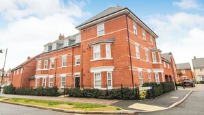 A multi-story residential building with a brick facade, multiple windows, and a gated entrance.