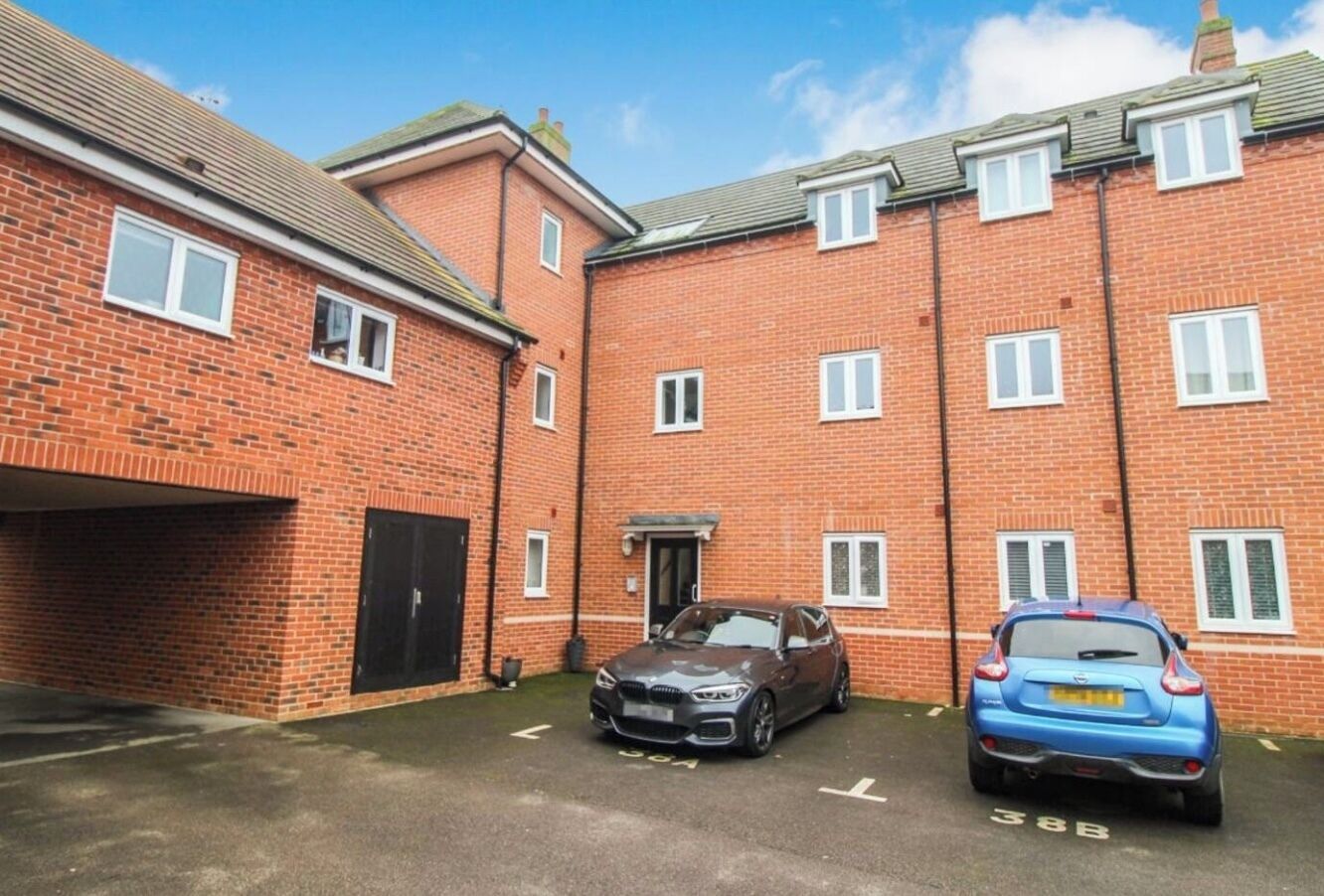 A brick building with two cars parked in front.