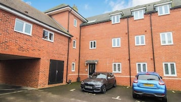 A brick building with two cars parked in front.