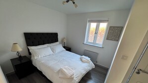 A bedroom with a bed, nightstands, a window, and a radiator.