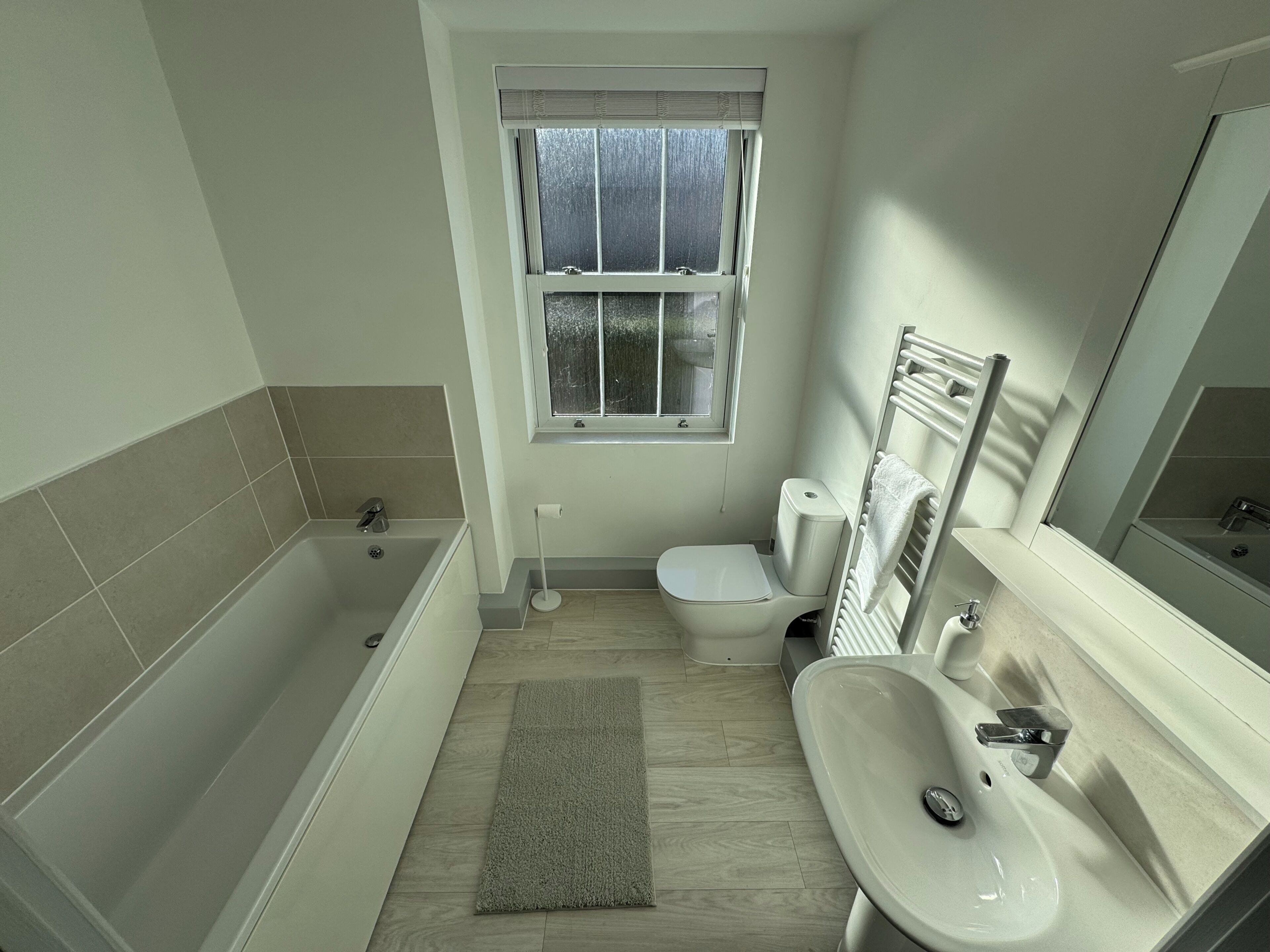Ein Badezimmer mit Badewanne, Toilette, Waschbecken und einem Fenster.