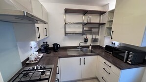 A compact kitchen with a gas stove, a microwave, and a sink.