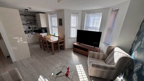A modern living room with a TV, sofa, and dining area.