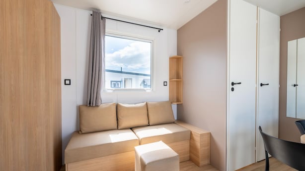 A modern room with a built-in sofa, a window with a view, and a door. - Caravan by the sea Blankenberge (Blankenberge)