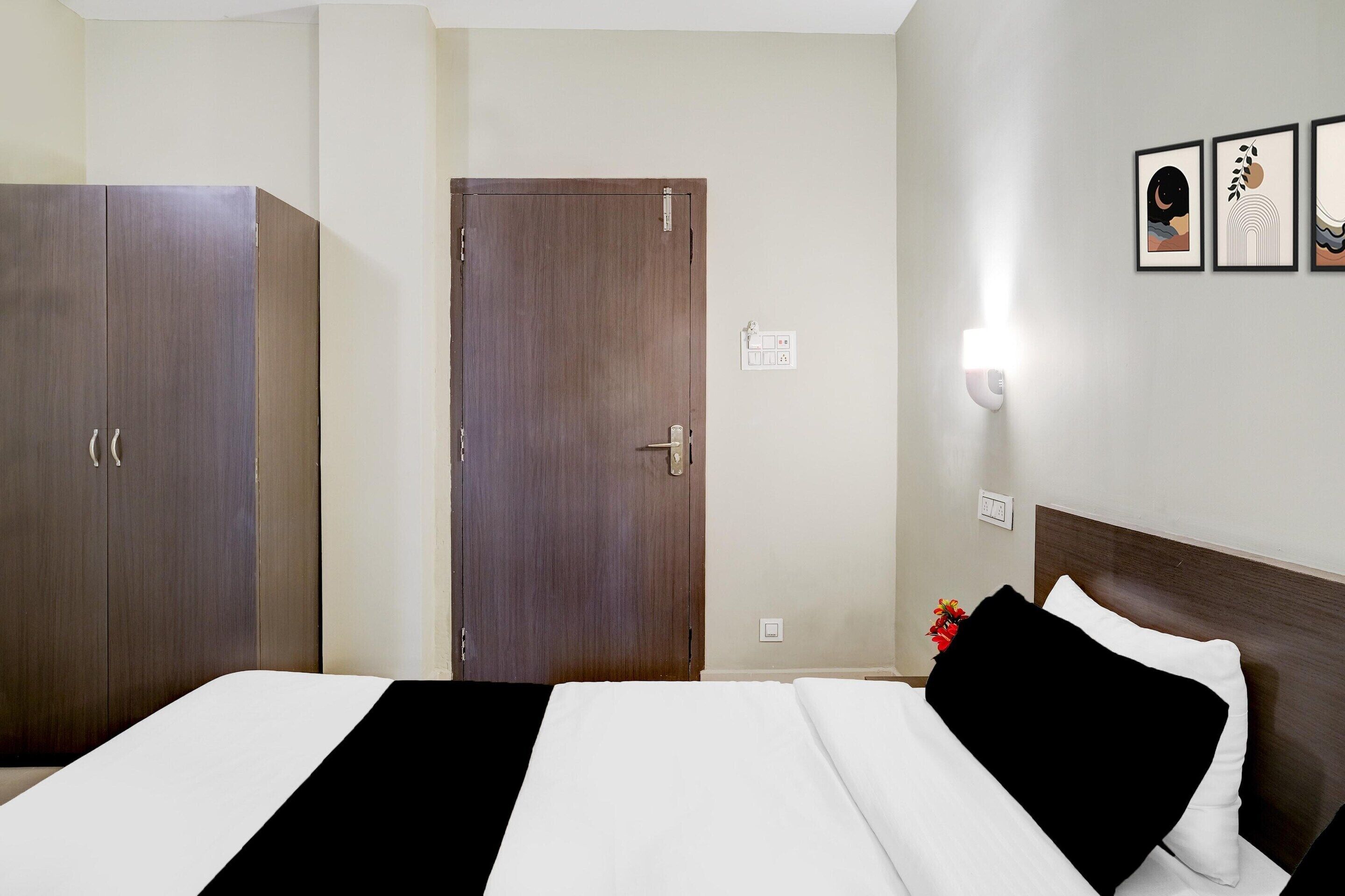 Et hotelværelse med seng, garderobe og dør.