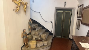 A staircase with stone steps, a green door, and wall-mounted light fixtures. - Villa Francescon (Borgo Valbelluna)