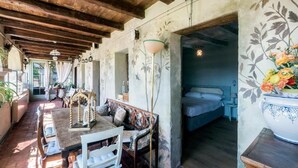 A room with a wooden ceiling, a bed, a table with chairs, and a large vase with flowers. - Villa Francescon (Borgo Valbelluna)