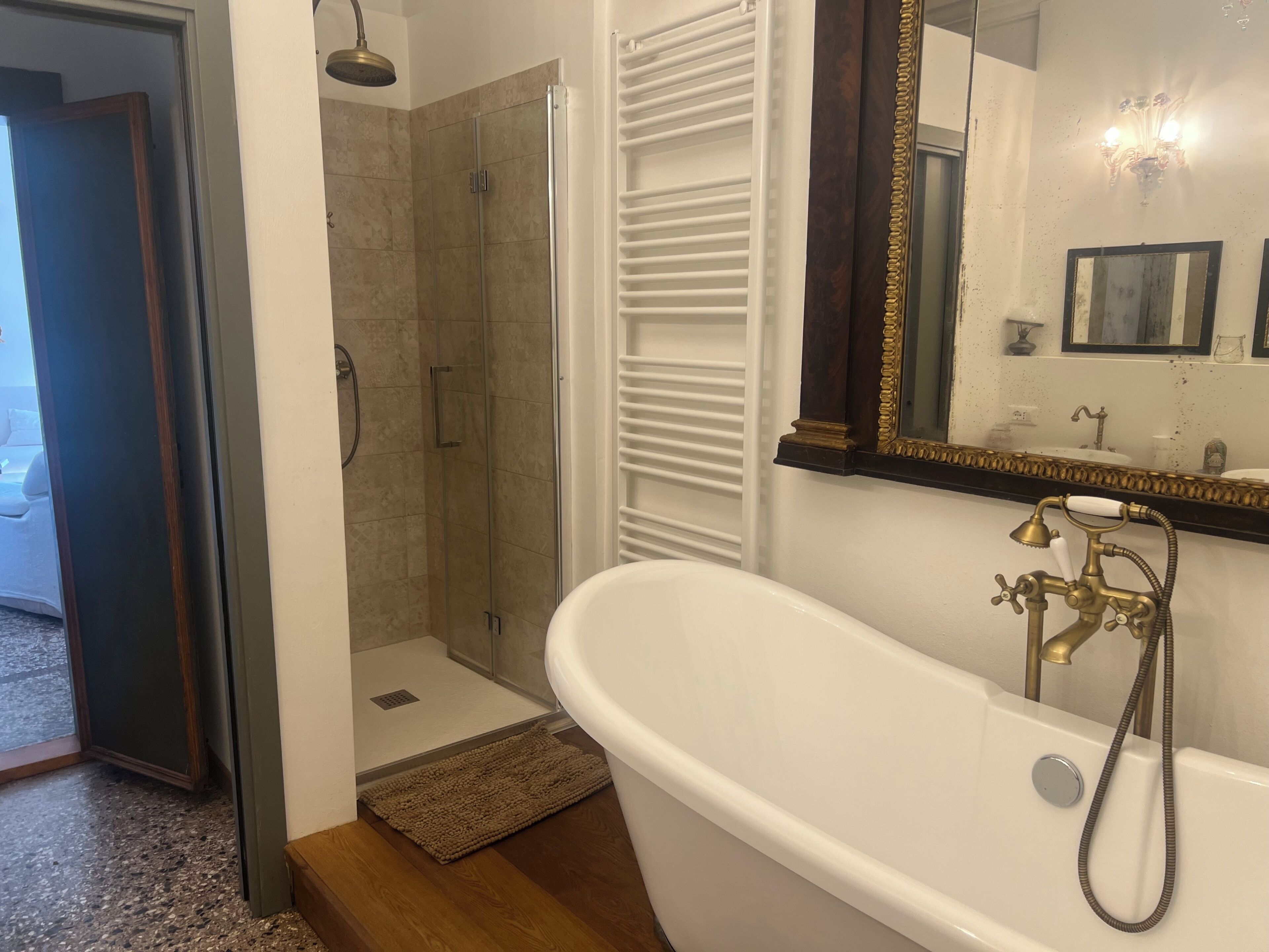 A bathroom with a bathtub, shower, and a mirror with a decorative frame.