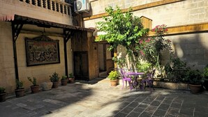 An outdoor courtyard with a wooden pergola, potted plants, and a table with chairs. - Gülizar Konukevi (Şanlıurfa)