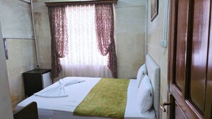 A room with a bed, a small desk, and a window with curtains. - Gülizar Konukevi (Şanlıurfa)