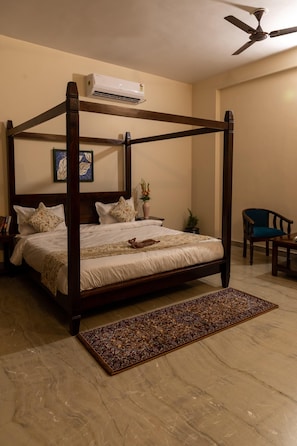 Un lit à baldaquin avec un ventilateur de plafond, une plante en pot et une petite table avec une chaise.