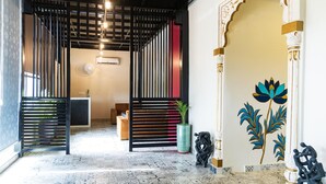 A modern interior with a patterned floor, a black and red partition, and a decorative wall with a plant and a statue.