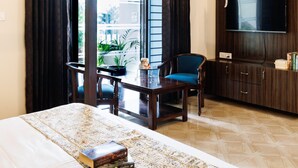 A hotel room with a bed, a desk, a chair, a TV, and a view of the outdoors.