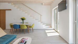 A modern interior with a staircase, dining area, and a flat-screen TV. - 3-bedroom Infinity Blue villa in fantastic Sunset Views close to Mykonos Town (Mykonos)