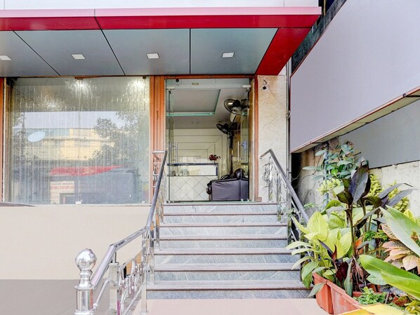 A hotel entrance with a staircase, a reception desk, and a plant area.