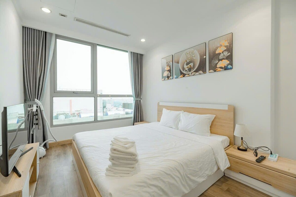 A hotel room with a bed, bedside table, lamp, and artwork on the wall.