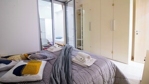 Un dormitorio con cama, armario y puerta corrediza de vidrio que da a un balcón.