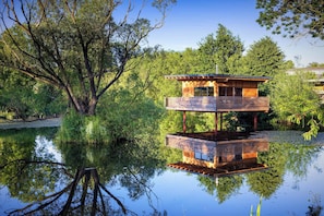 A multi-level wooden structure with a reflective water surface, surrounded by trees. - Besonderes Tinyhouse (Grossharthau)