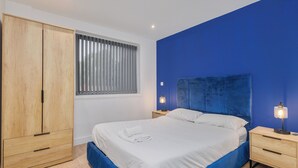 A bedroom with a bed, wooden wardrobe, bedside tables, and a window with blinds. - Beautiful 1-bedroom apartment in the heart of Birmingham (Birmingham)