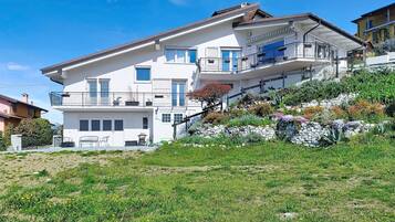 Ein zweistöckiges Haus mit Balkon, einer Steinschmalseite und einem Garten mit verschiedenen Pflanzen.
