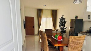 A dining area with a wooden table, wicker chairs, a refrigerator, and a kitchen counter. - Casa Brisa Caribe Cabrera Perfect for Family & Friends (Cabrera)