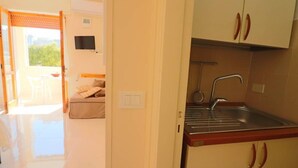 Una cocina con un lavamanos, armarios y un televisor.