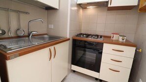 Una cocina compacta con un lavamanos, estufa, horno y armarios.