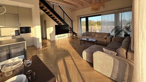A spacious living area with a sofa, coffee table, and a TV on a stand. A staircase leads to an upper level. - Stylish Japandi Home | Sleeps 8 | Bathrooms 2 | Garden (Kołczewo)