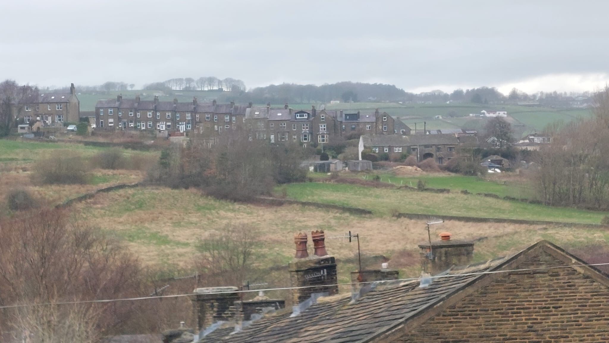 Zona residencial con casas, un campo y un edificio lejano.