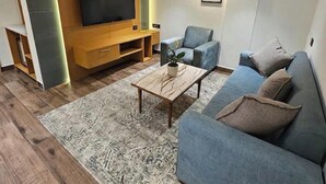 A modern living room with a flat-screen TV, a sofa, a chair, and a coffee table. - BluSalzz Collection Casa Onze Goa (Calangute)