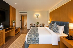 A hotel room with a bed, bedside tables, a TV, a desk, and a chair. - BluSalzz Collection Casa Onze Goa (Calangute)