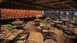 An outdoor restaurant with tables set for dining, a bar area, and a decorative ceiling. - BluSalzz Collection Casa Onze Goa (Calangute)