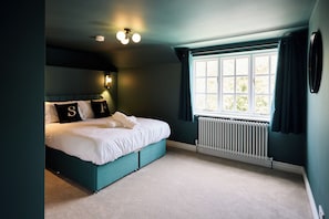Ein Schlafzimmer mit Bett, einem Fenster mit Vorhängen, einem Heizkörper und einer Wandleuchte.