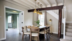 A dining area with a wooden table, chairs, pendant lights, and a staircase. - Daisy Cottage | Sands Farm (Wilton)